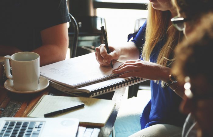 Person writing on notebook over coffee